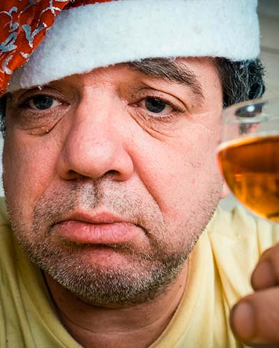 грустный мужчина с алкоголем в праздничной шапке